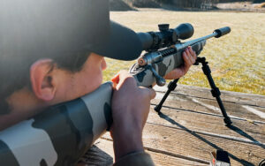 Main aiming a rifle with suppressor